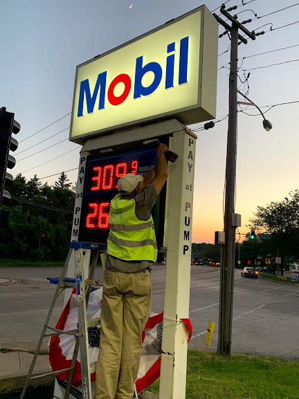 malik lighting employee repairing a mobil gas station sign
